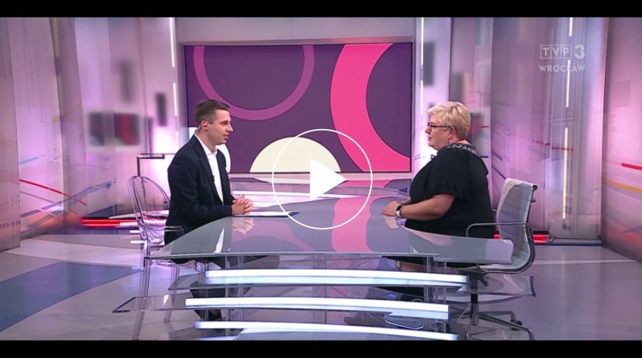 dwie osoby przy stole w studiu telewizyjnym