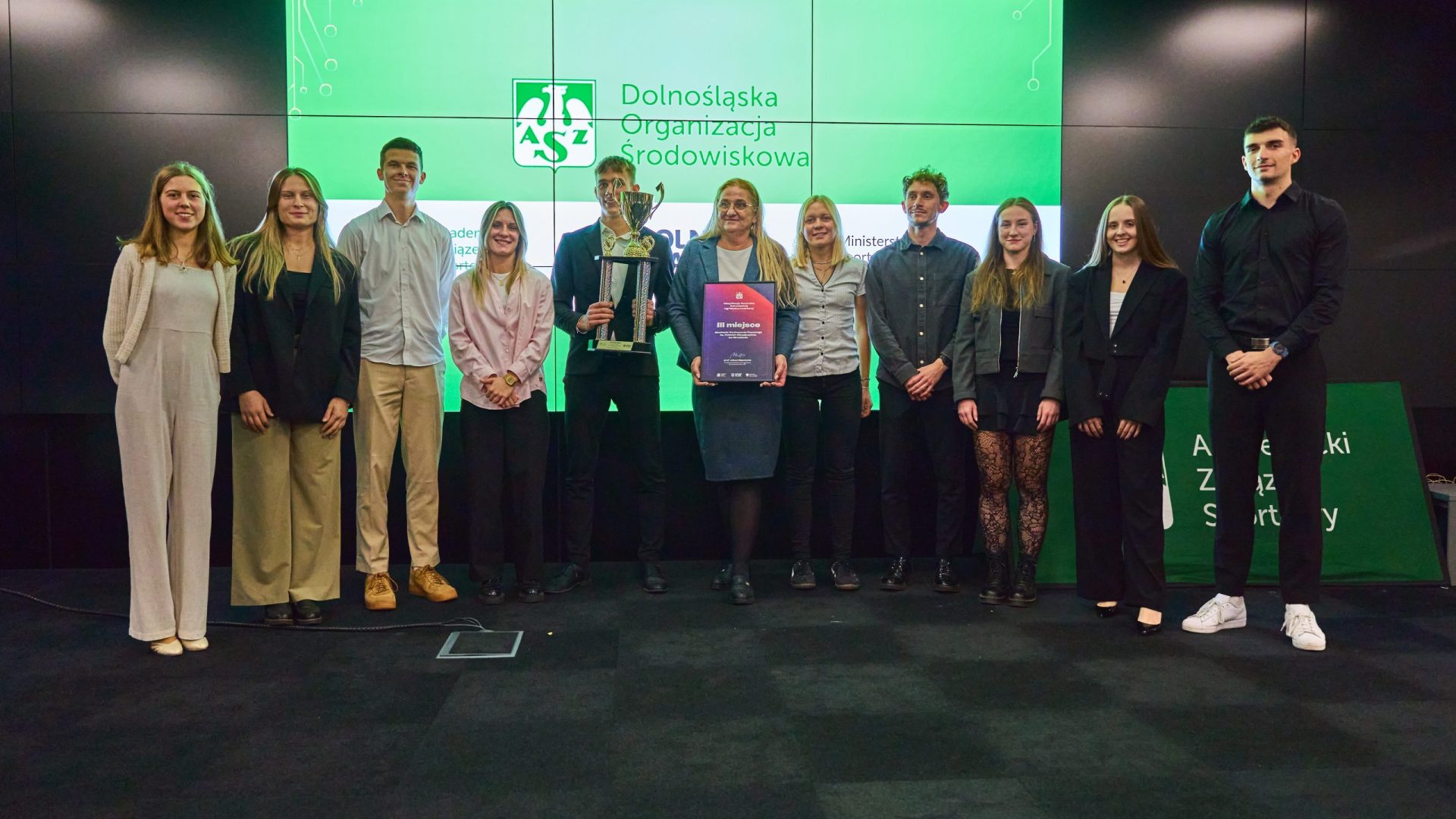 kilka osób na scenie, z tyłu ekran