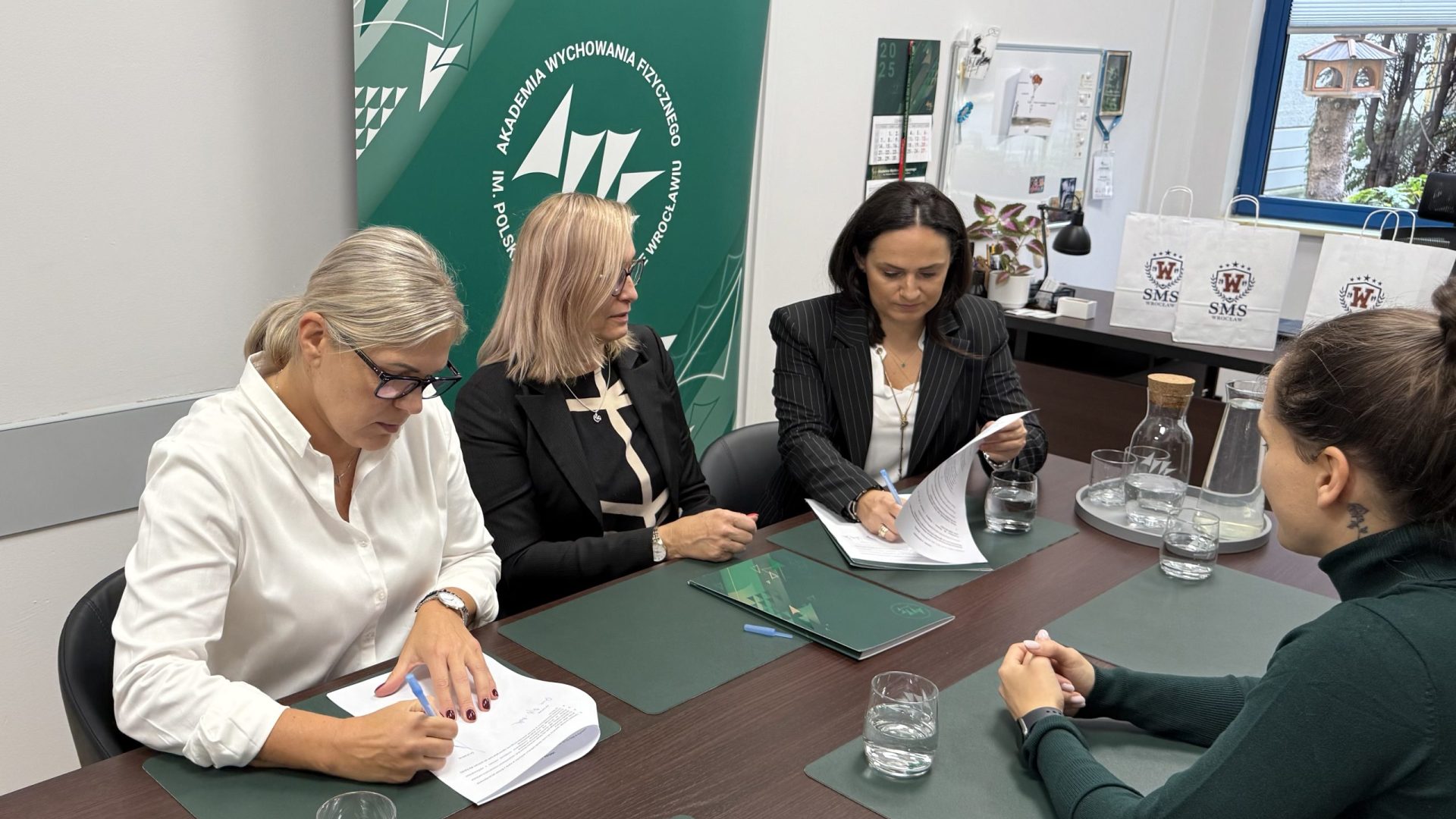 trzy kobiety przy stole z jednej strony, z drugiej jedna i mężczyzna, trwa podpisanie umów