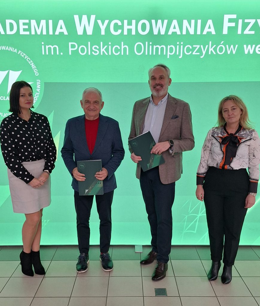 na zielonym tle czworo ludzi pozujących do zdjęcia