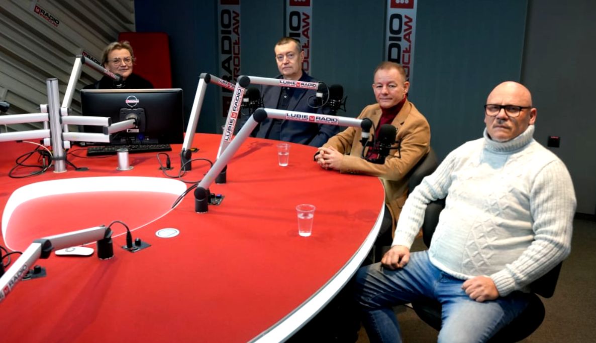 mężczyźni i kobieta w studiu radiowym, czerwony stół i mikrofony