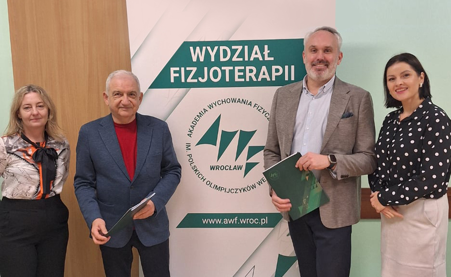 cztery osoby pozują do zdjęcia na tle rollupu AWF