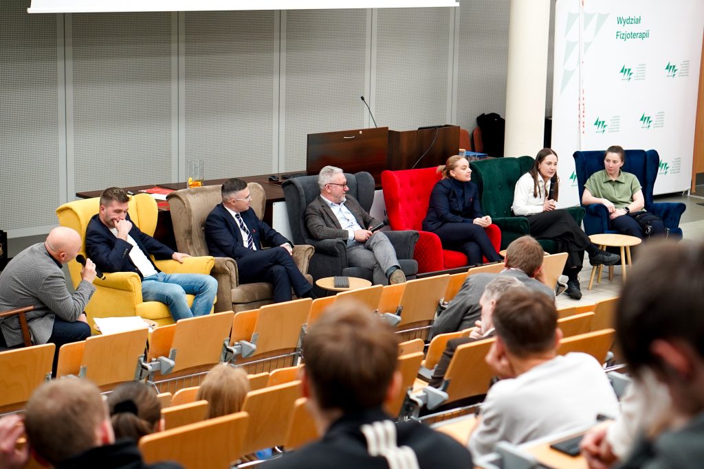 kilka osób siedzi na fotelach, debata