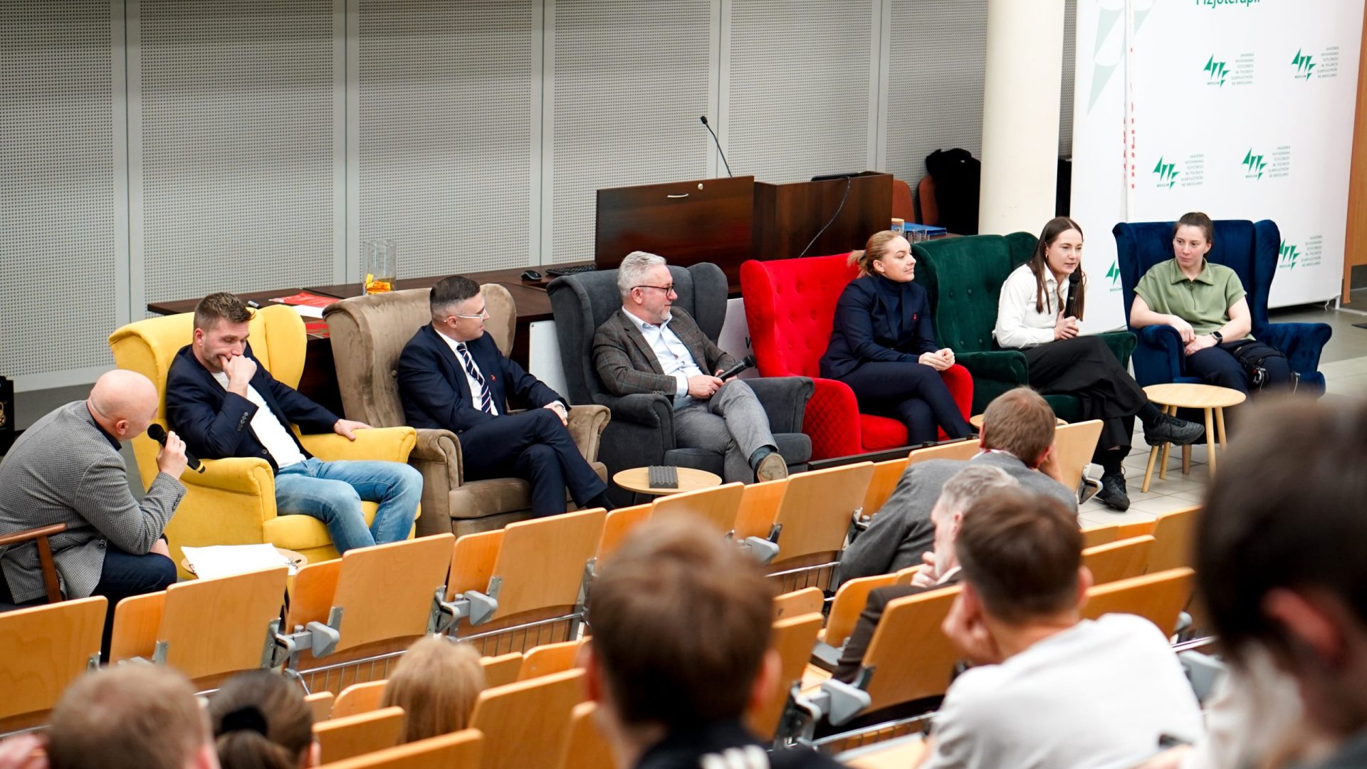 kilka osób siedzi na fotelach, debata