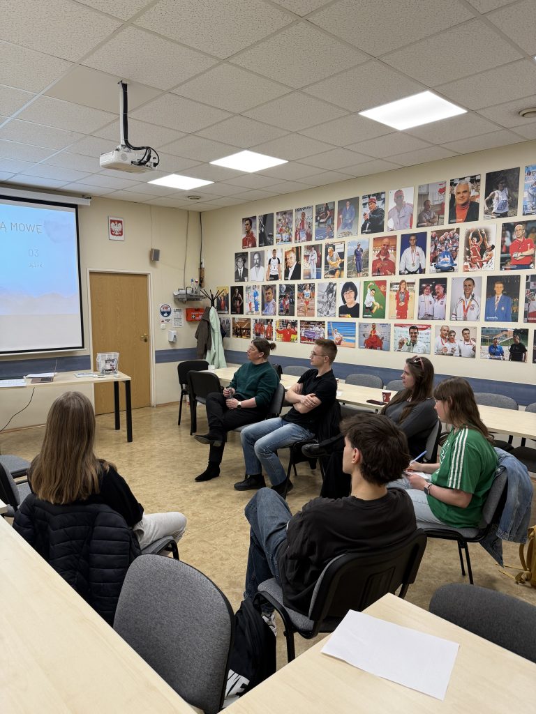 Warsztaty dla studentów AWF, siedzą w półkolu i słuchają