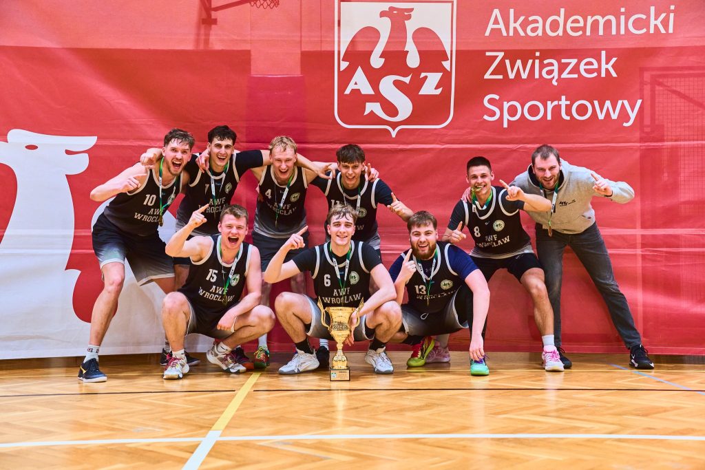 koszykarze pozują do zdjęcia na czerwonej ściance po zwycięstwie