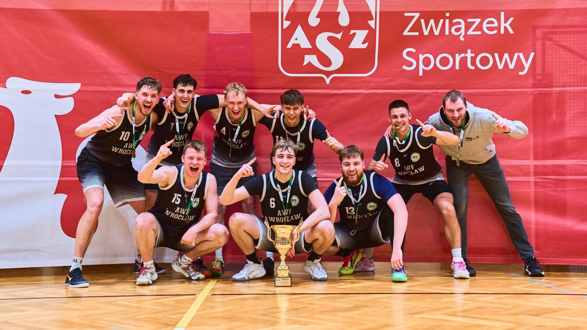 koszykarze pozują do zdjęcia na czerwonej ściance po zwycięstwie